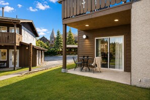 A residential building with a patio area, a covered outdoor seating space, and a large sliding glass door leading to a backyard. - Edelweiss Escape 1 Bedroom Condo (Leavenworth)