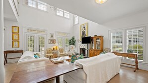 A spacious living room with a large window, a fireplace, and a television. - Sunny Days 5 Bedroom Home (Georgetown)