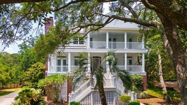 A two-story house with a front porch, a small staircase, and a circular driveway. - Sunny Days 5 Bedroom Home (Georgetown)