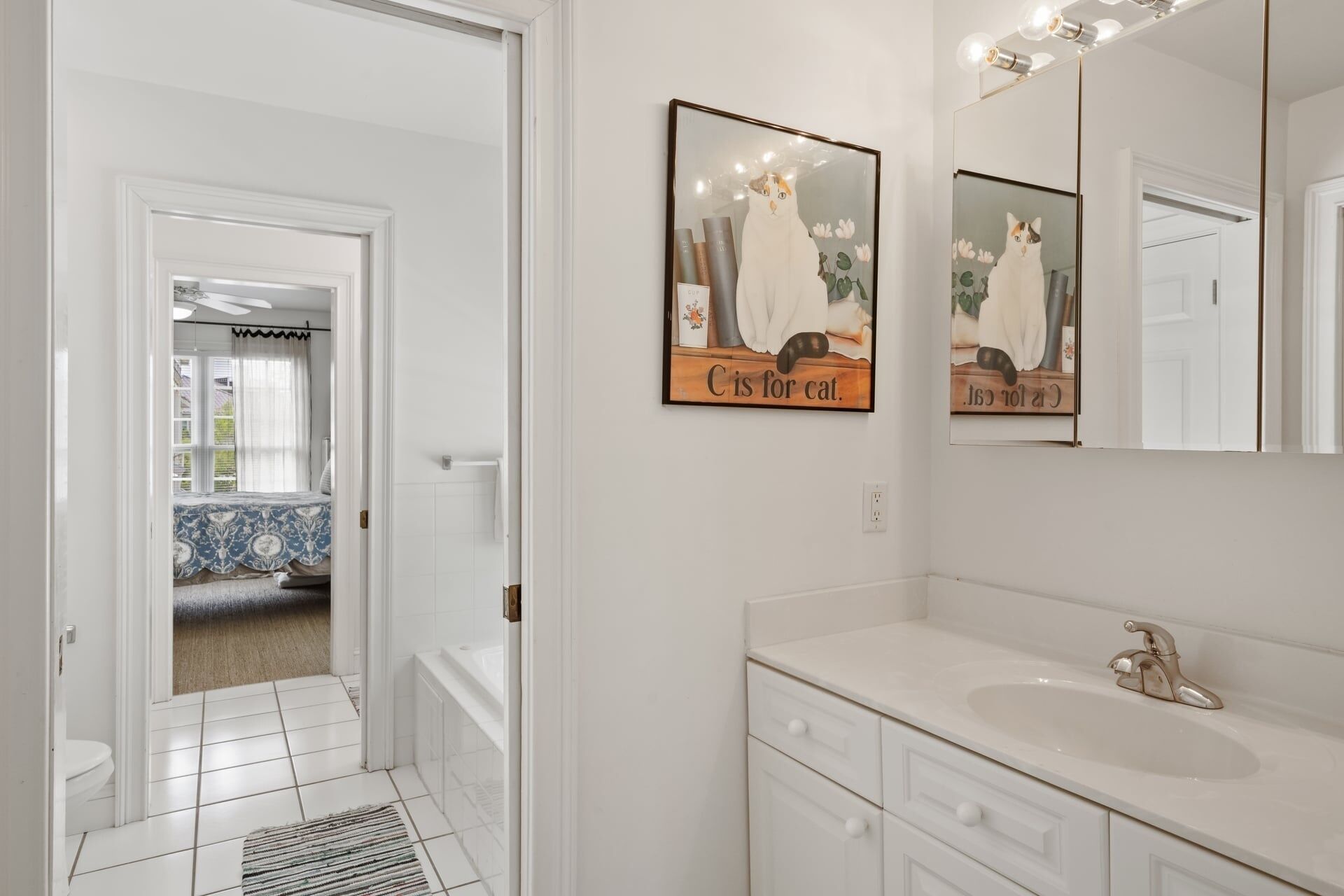 A bathroom with a white sink, a mirror, and two framed pictures on the wall.