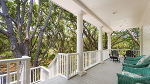 A covered porch with white railings, a white ceiling, and a view of a forested area. - Sunny Days 5 Bedroom Home (Georgetown)