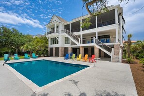 A two-story building with a pool, outdoor seating, and a staircase leading to the upper level. - Cornfed Pelican 9 Bedroom Home (Georgetown)