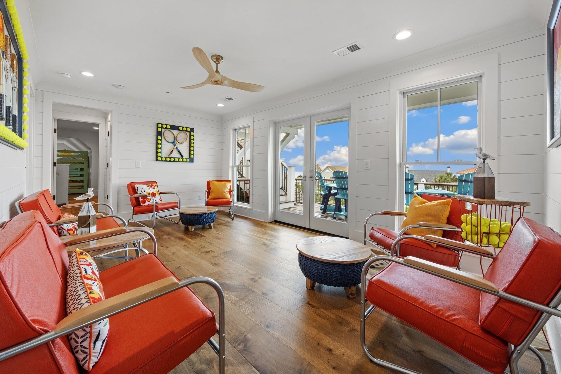 A spacious living room with a high ceiling, a ceiling fan, and large windows offering a view of the outside.