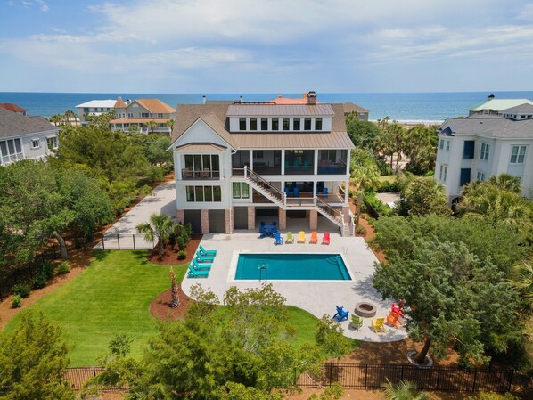 A two-story house with a large front yard, a swimming pool, and a view of the ocean. - Cornfed Pelican 9 Bedroom Home (Georgetown)