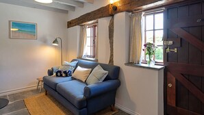 A cozy living room with a blue sofa, a lamp, and a painting on the wall.