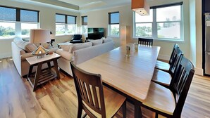 Un salon moderne comprenant un coin repas, de grandes fenêtres et un téléviseur à écran plat.
