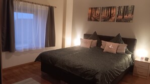 A bedroom with a bed, a nightstand, a lamp, and a window with curtains.
