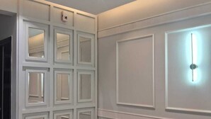 Un couloir moderne avec un mur blanc, un éclairage encastré et un banc.