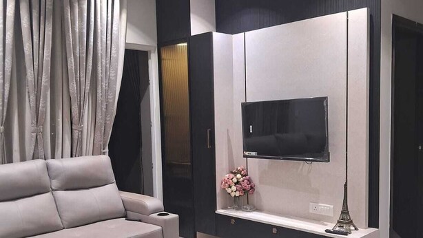 Un salon moderne avec un canapé, un téléviseur fixé au mur, un ventilateur de plafond et un vase décoratif.