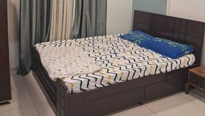 Une chambre à coucher avec un lit, des rideaux, un ventilateur de plafond et un sol carrelé.
