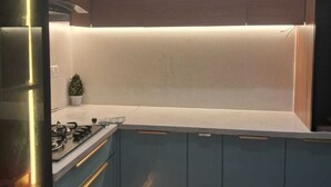 Une cuisine moderne avec des meubles bleus, un plan de travail blanc et une cuisinière à gaz.