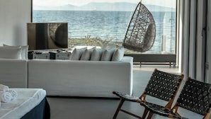 Un dormitorio moderno con un ventanal grande, un sillón colgante, un sofá y un televisor.