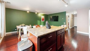 A modern kitchen with a granite countertop, dark wooden cabinets, and a dining area with a white table and chairs. - Cozy Condo, Sleeps 2! (Chicago)