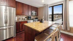 A modern kitchen with granite countertops, stainless steel appliances, and wooden cabinets. - Cozy Condo, Sleeps 2! (Chicago)