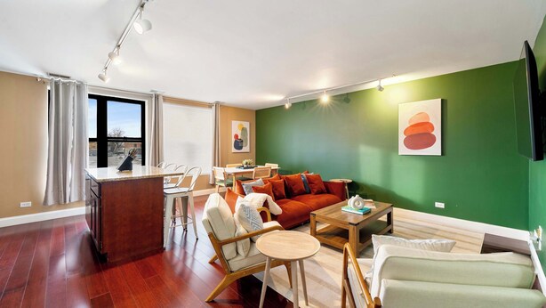 A modern living room with a sofa, chairs, a coffee table, and a dining area. - Cozy Condo, Sleeps 2! (Chicago)