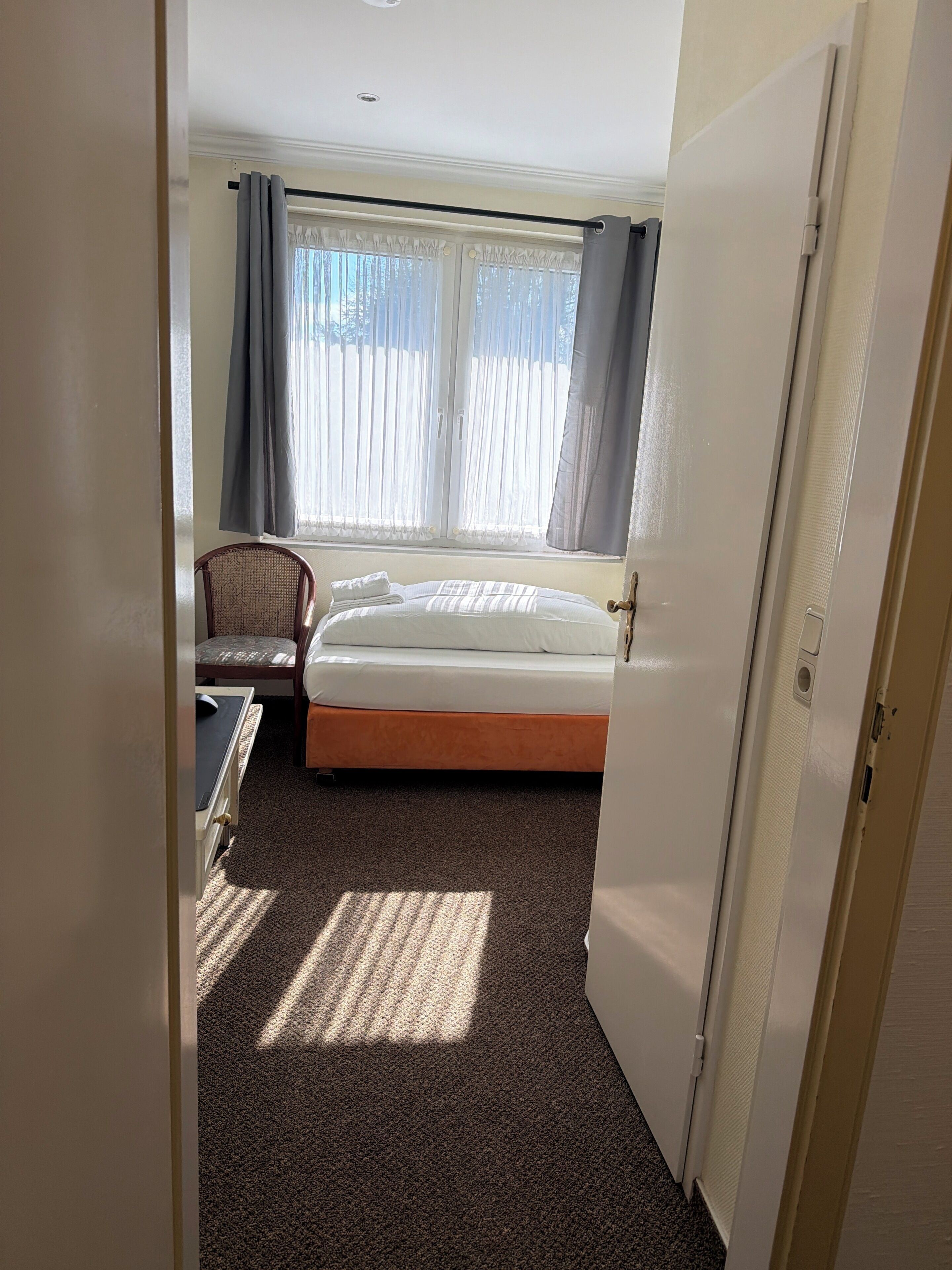 A hotel room with a bed, a desk, and a chair.