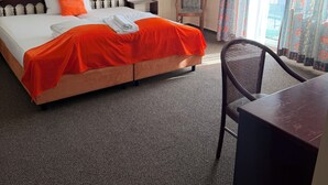 Habitación de hotel con cama, una silla, un escritorio y un cuadro en la pared.