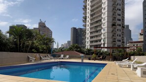 Une piscine sur le toit, avec un sol carrelé et des chaises longues.
