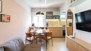 Une cuisine moderne avec un coin repas, un canapé et un téléviseur fixé au mur.