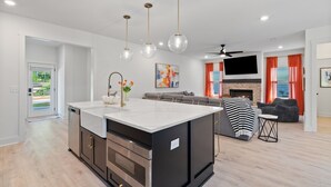 Una cocina moderna con una isla central, electrodomésticos de acero inoxidable e iluminación colgante.