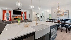 Una cocina moderna con una isla central, electrodomésticos integrados e iluminación colgante.