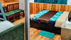 Ein Zimmer mit einem Bett, einem Holz-Kopfteil, einem an einer Holzwand montierten Fernseher, einem Deckenventilator und einem Fenster mit türkisfarbenen Vorhängen.