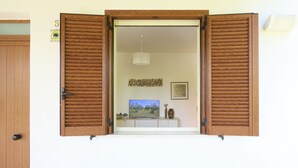 Una habitación con puerta de madera, televisor sobre una mesita y lámpara colgante.