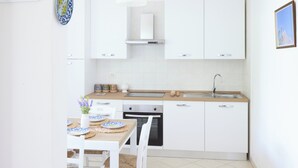 Una cocina moderna con armarios blancos, encimera de madera, horno empotrado y un lavabo.
