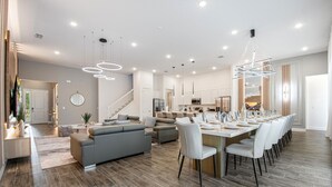 A spacious living area with a dining table, sofas, and a kitchen in the background. - 4001SB Sonoma (Kissimmee)