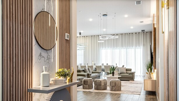 A modern living room with a sofa set, ottomans, and a coffee table. There is a round mirror on a wall and a wooden panel on the left. - 4001SB Sonoma (Kissimmee)