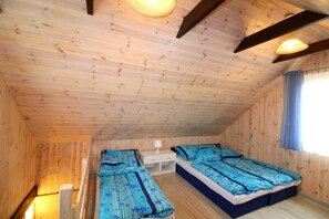A wooden interior with two beds, a nightstand, and a window with curtains.
