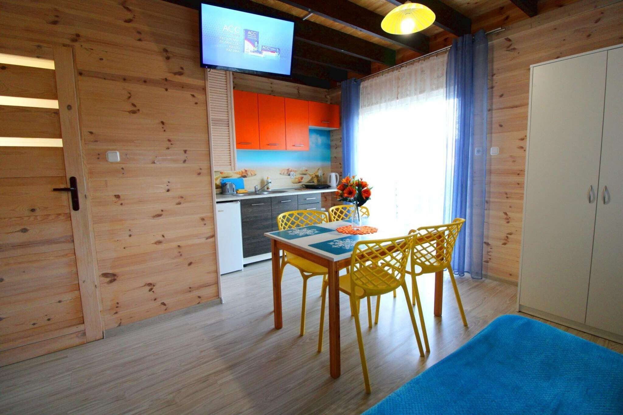 A wooden interior with a dining area, kitchen, and a television mounted on the wall.