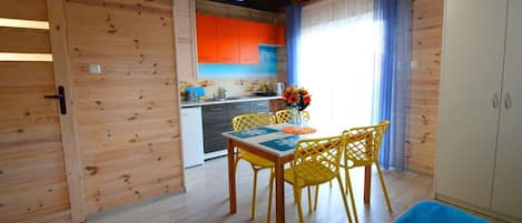 A wooden interior with a dining area, kitchen, and a television mounted on the wall.