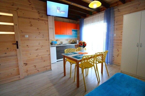 Un interior de madera con comedor, cocina y un televisor montado en la pared.