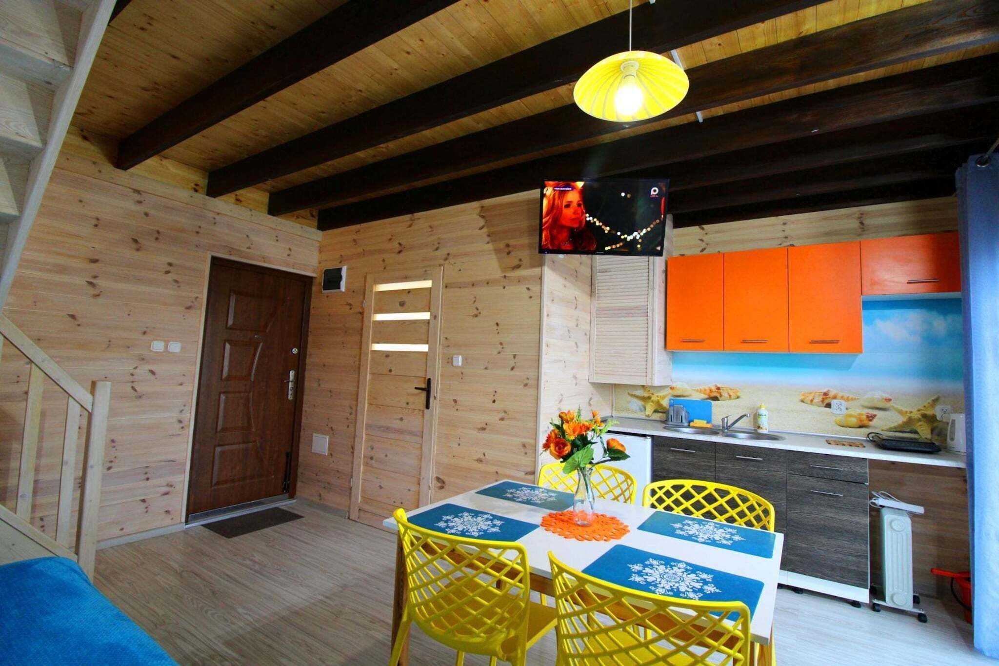 A wooden interior with a dining table, chairs, and a kitchen area with orange cabinets.
