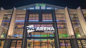 Das äußere Erscheinungsbild des Arena Wembley Stadions bei Nacht mit beleuchteter Beschilderung.