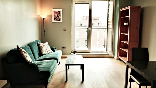 A living room with a sofa, coffee table, and a cabinet. - Central 2BR Birmingham Apt - Free Parking (Birmingham)