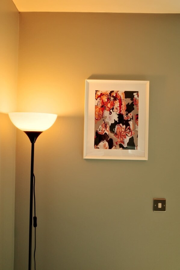 Una habitación con un cuadro colgado en la pared y una lámpara de pie.
