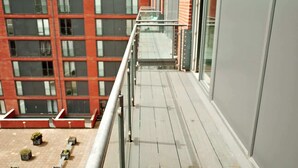 A modern building with a balcony, large windows, and a red brick facade. - Central 2BR Birmingham Apt - Free Parking (Birmingham)