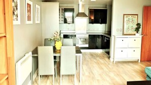 A modern kitchen with white cabinets, a dining area with a table and chairs, and a living space with a sofa. - Central 2BR Birmingham Apt - Free Parking (Birmingham)