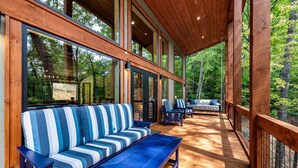 A covered deck with wooden flooring, blue and white striped sofas, and chairs. - Olivers Modern Twist- Cherry Log GA (Cherry Log)
