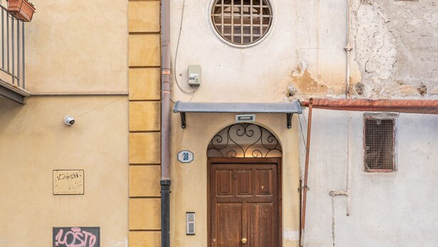 A building with a wooden door, a small window with a metal grille, and a number '38' sign on the wall. - Gorizia Apartment by Wonderful Italy (Palermo)