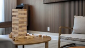 Ein Turm aus Holzblöcken auf einem runden Tisch in einem Raum mit einer Holzschindelleiste und einem gepolsterten Stuhl.