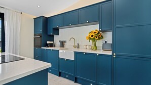 Una cocina moderna con armarios azules, encimera blanca y un jarrón con girasoles.