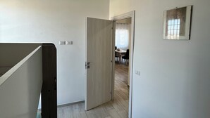 Un pasillo con piso de madera, una puerta que da a un comedor y un espejo pequeño en la pared.