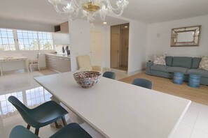 Ein modernes Wohnzimmer mit Esstisch, Stühlen, einer Couch und einer Kronleuchter.
