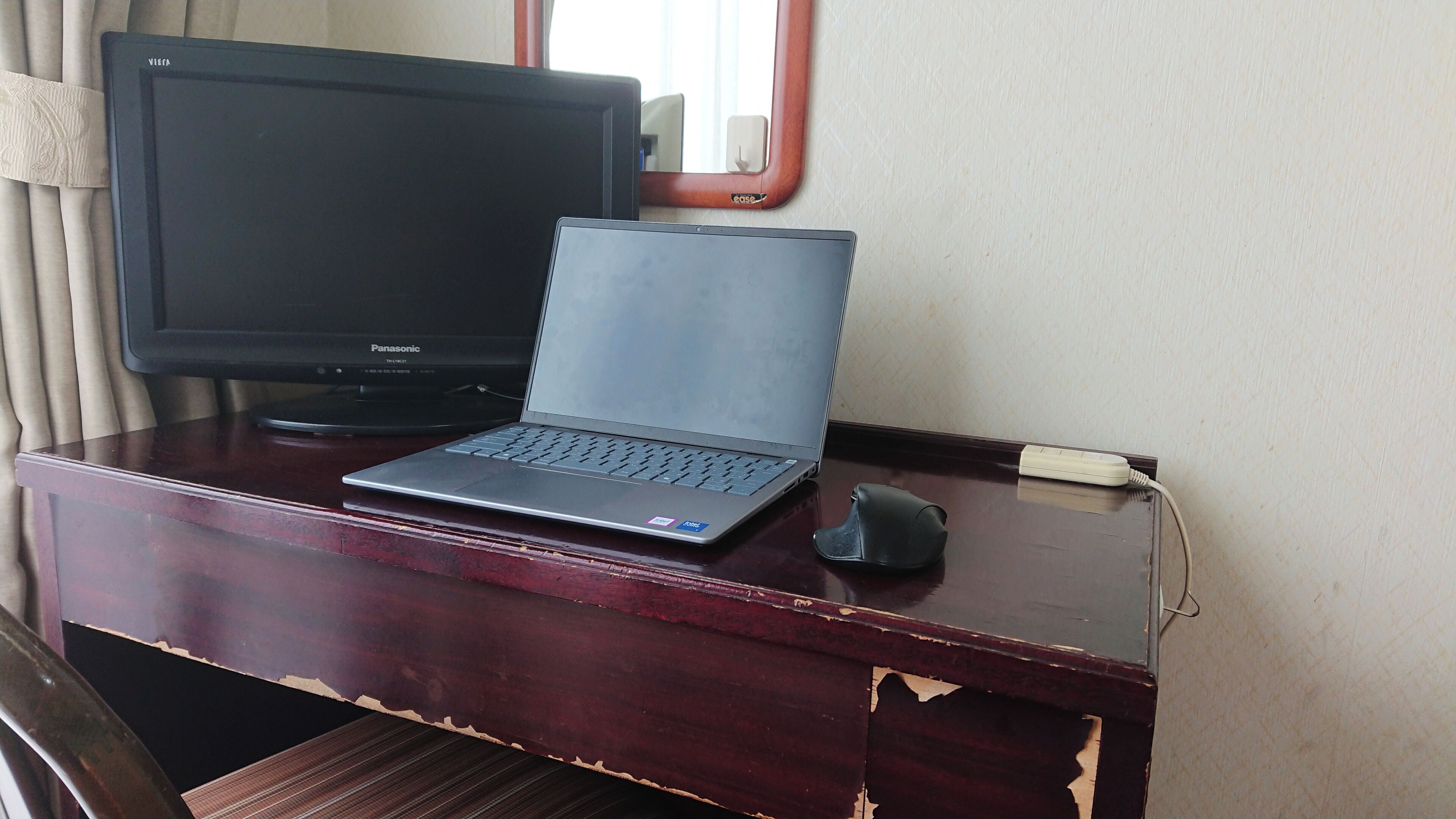 A wooden desk with a laptop, a monitor, and a mouse.