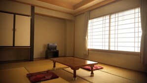 A traditional Japanese room with tatami flooring, a low wooden table, a television, and sliding doors. - Hotel Yuou Onsen  (Kofu)