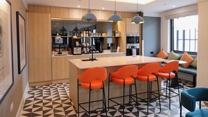 A modern kitchen with a central island, bar stools, and a seating area with a view. - Student Only Bargate House (Southampton)