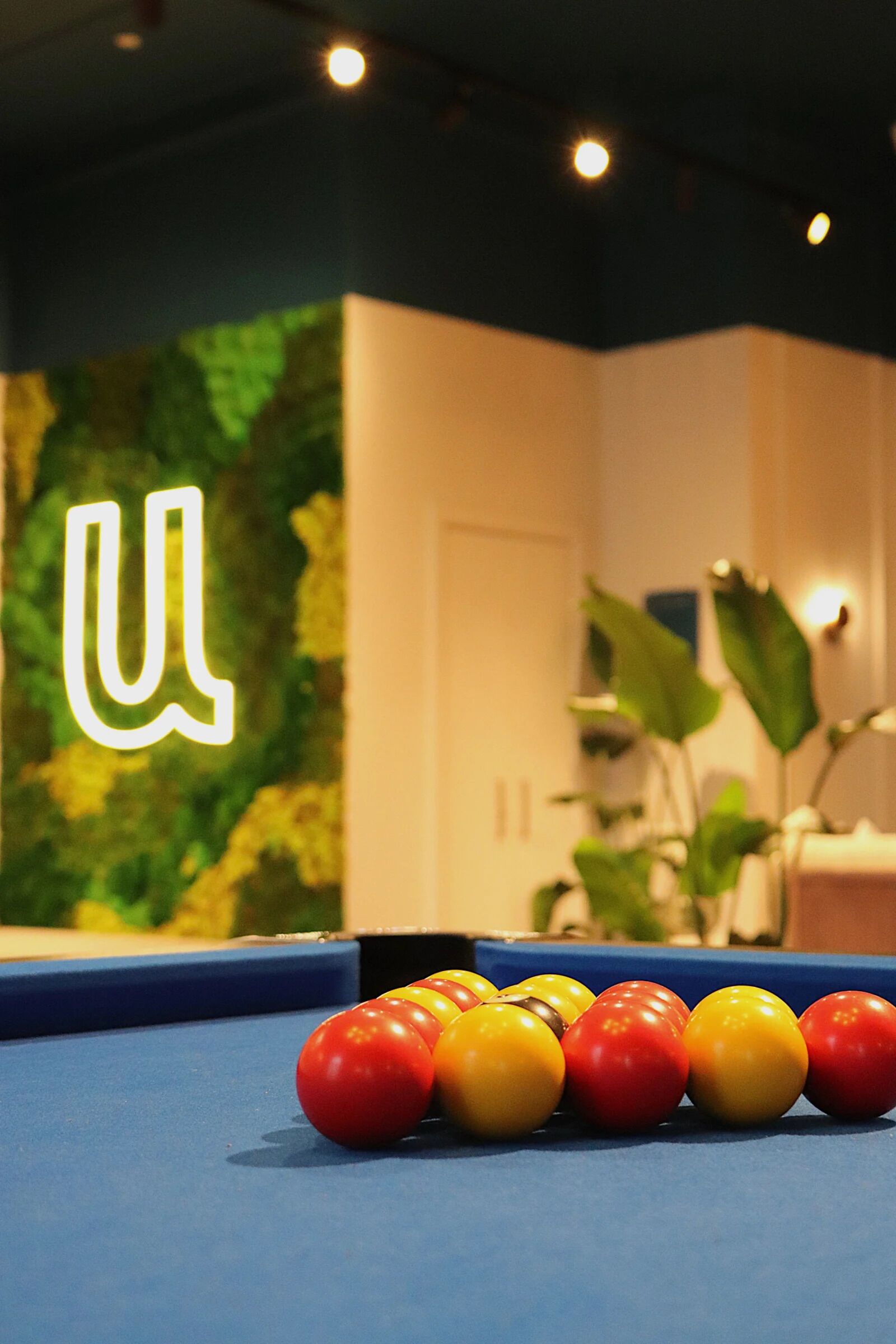 A pool table with a green wall and a door in the background.